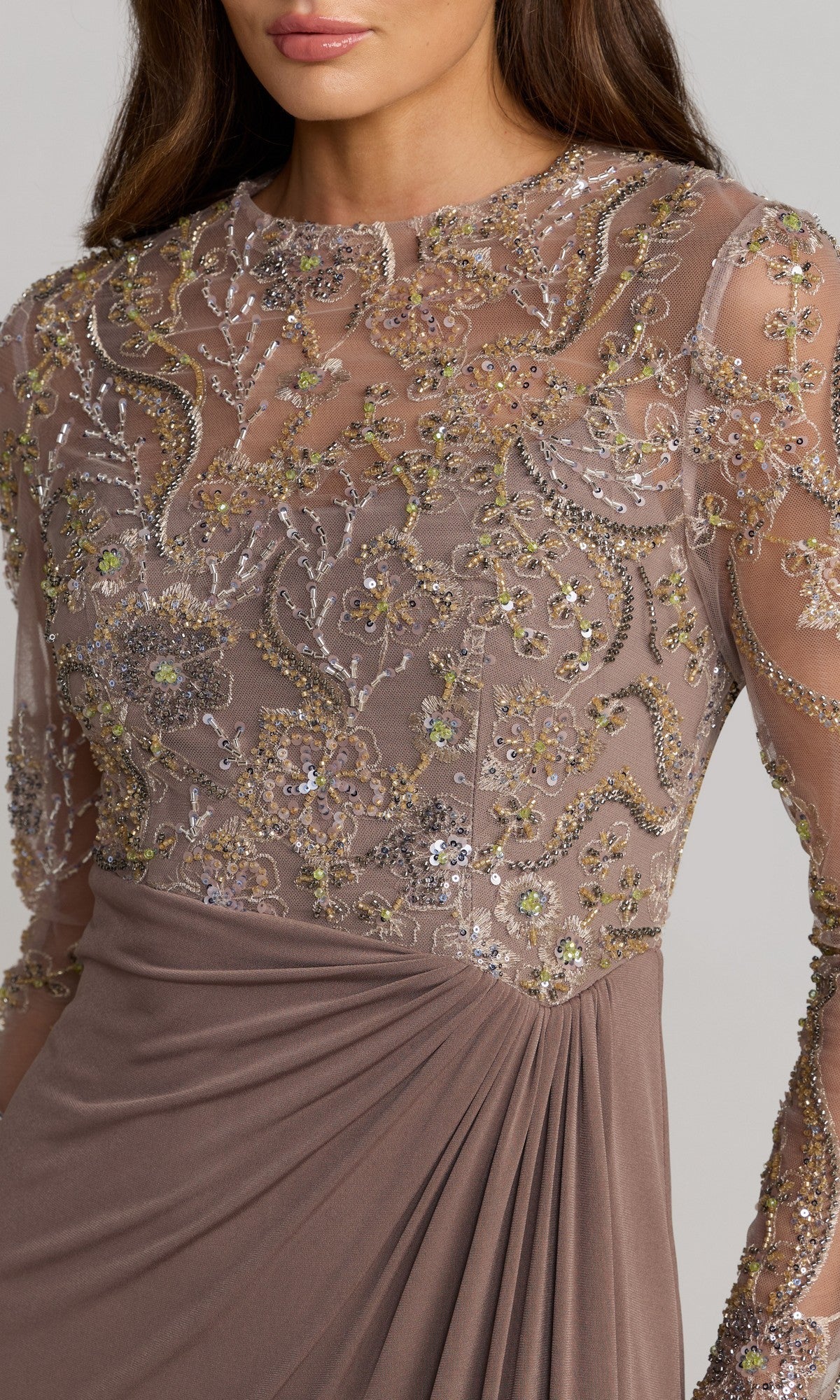 A woman wears the Long Formal Dress: Mac Duggal 69121, showcasing a sequin embroidered bodice adorned with intricate floral beadwork and dazzling embellishments on sheer long sleeves. This stunning gown exudes timeless elegance.
